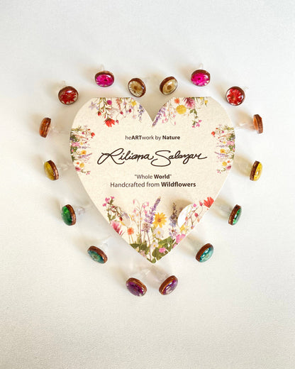Heart-shaped packaging with floral design and small wildflower framed in wood earrings in rainbow color order on a white background